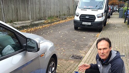 Paul Lorber pointing at a blown away blue recycling bag